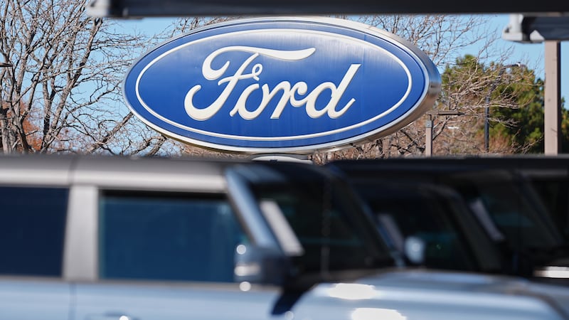 The company logo hangs over a row of unsold 2026 Bronco utility vehicles on the lot of a Ford...